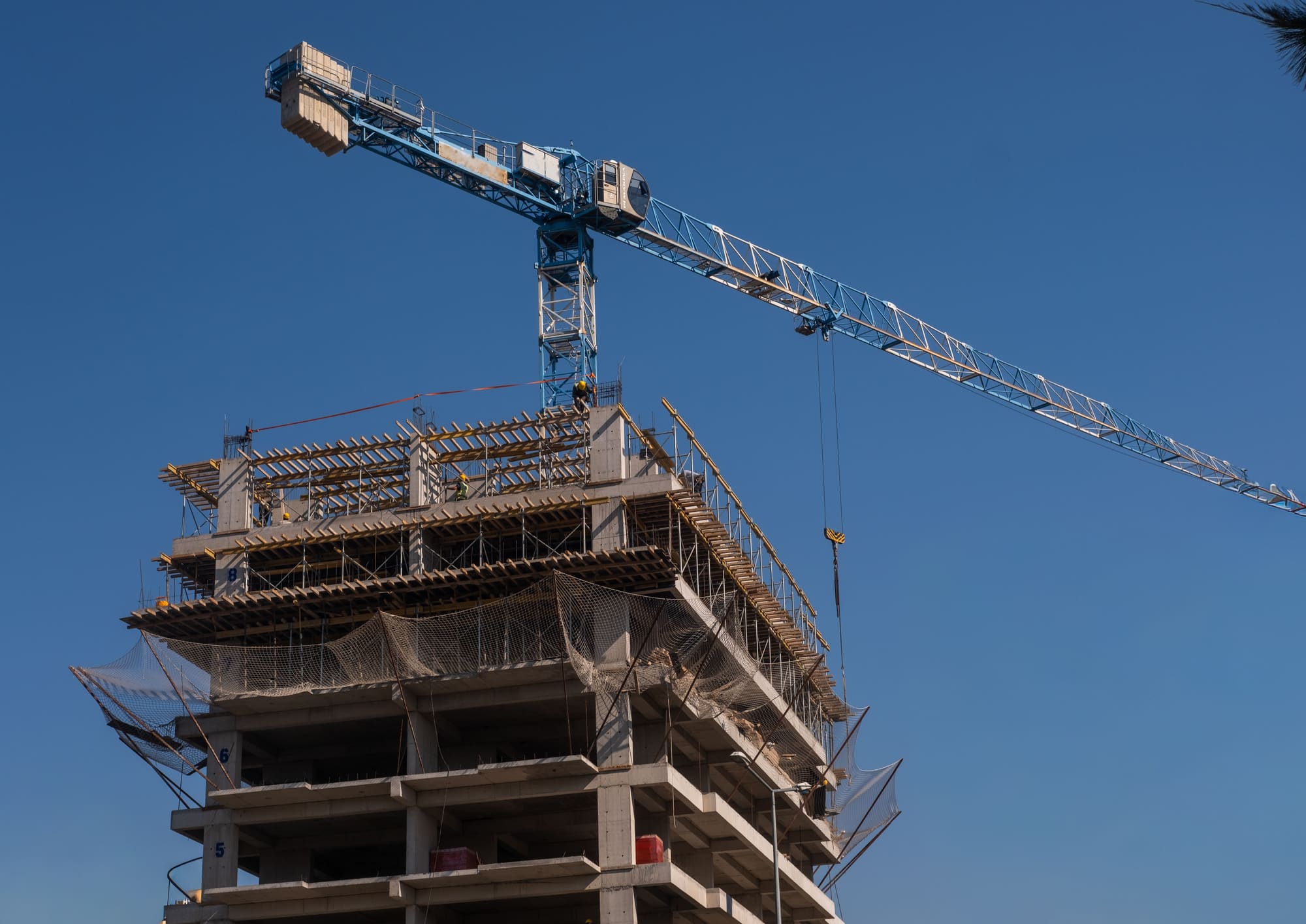 Estructura de concreto vaciado en sitio de una torre en construcción, con la grúa torre encima contra un cielo despejado