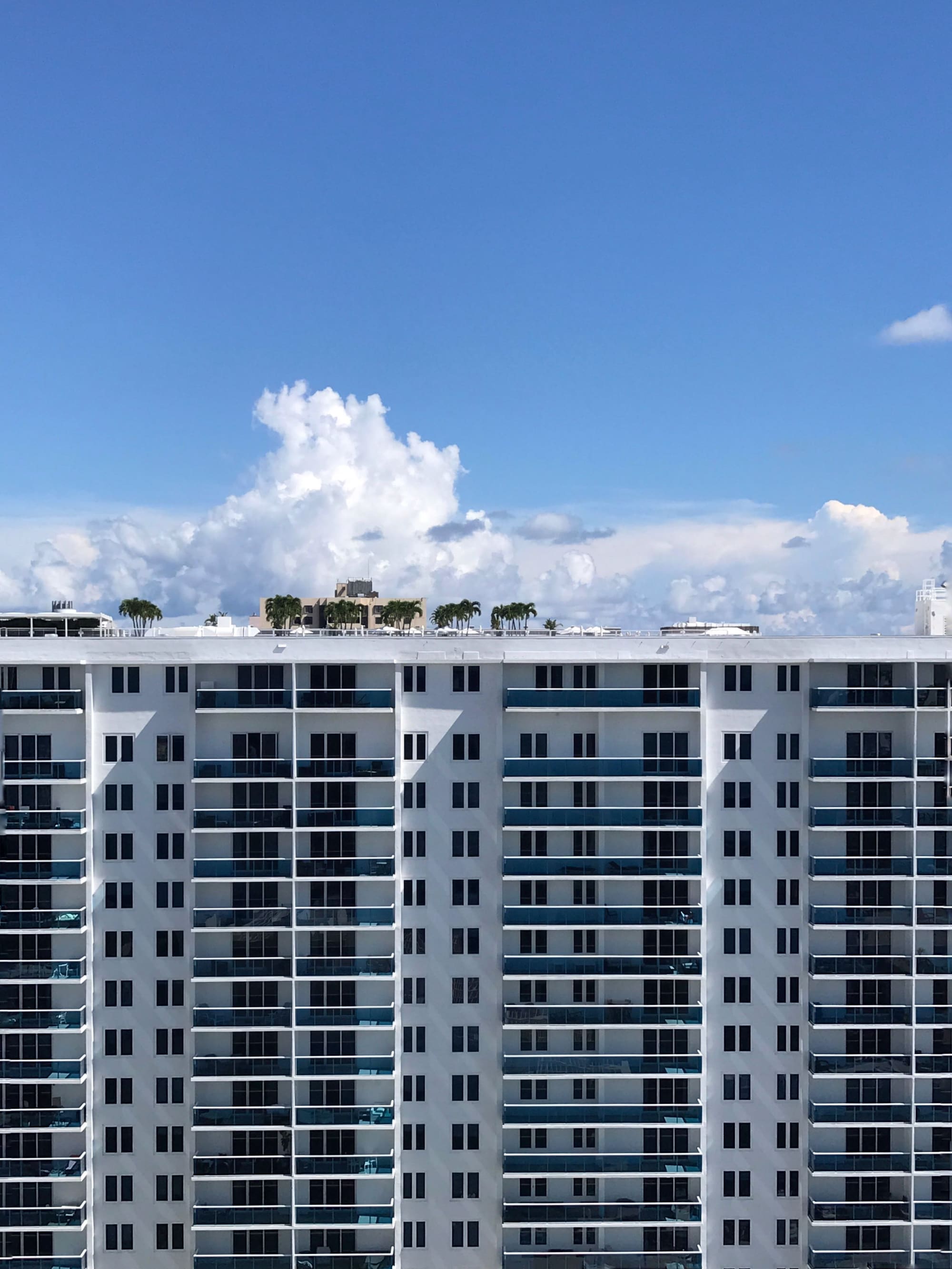 Edificio residencial blanco con filas de balcones bajo un cielo de verano