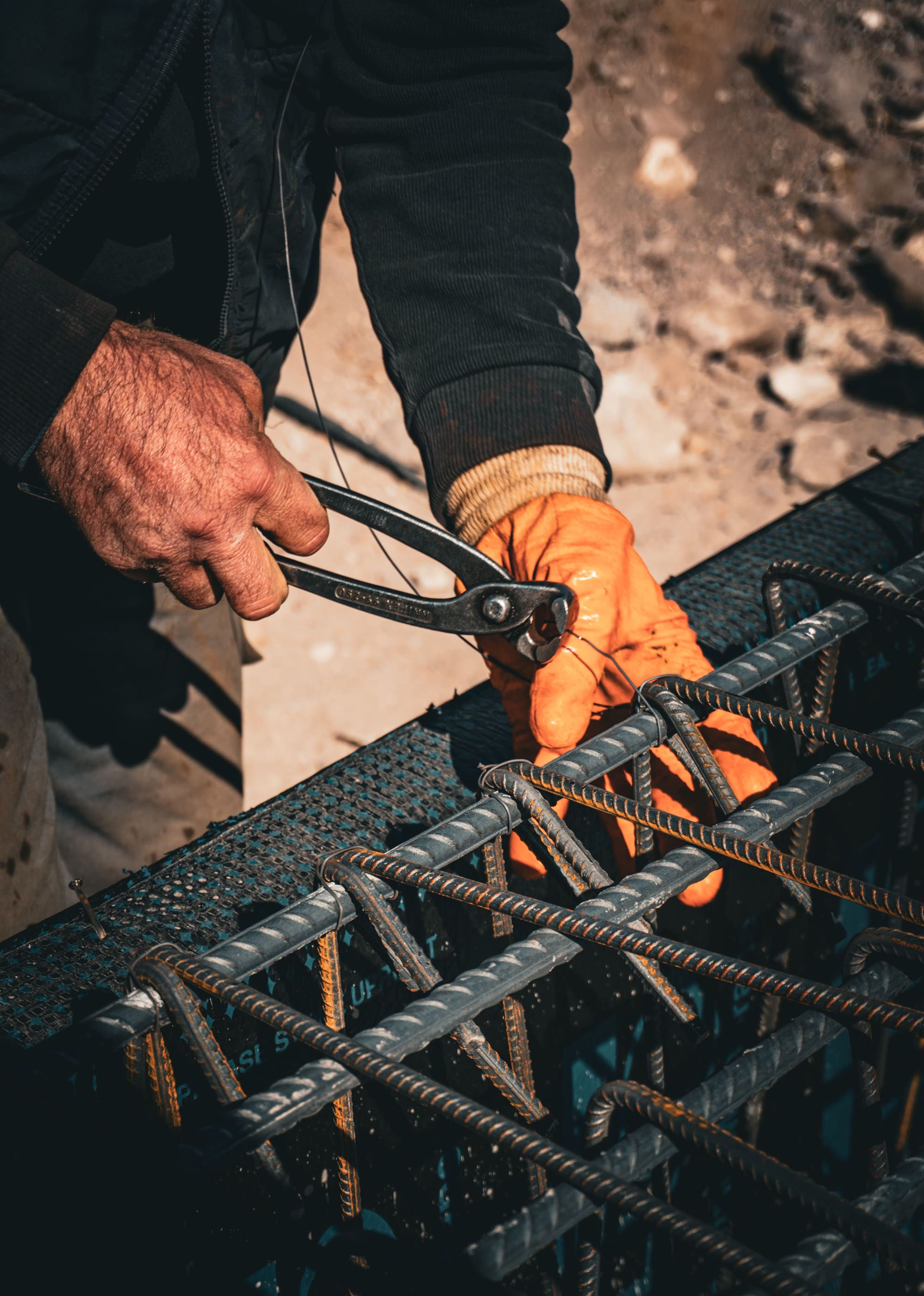 Hands tying a reinforcement intersection with pliers