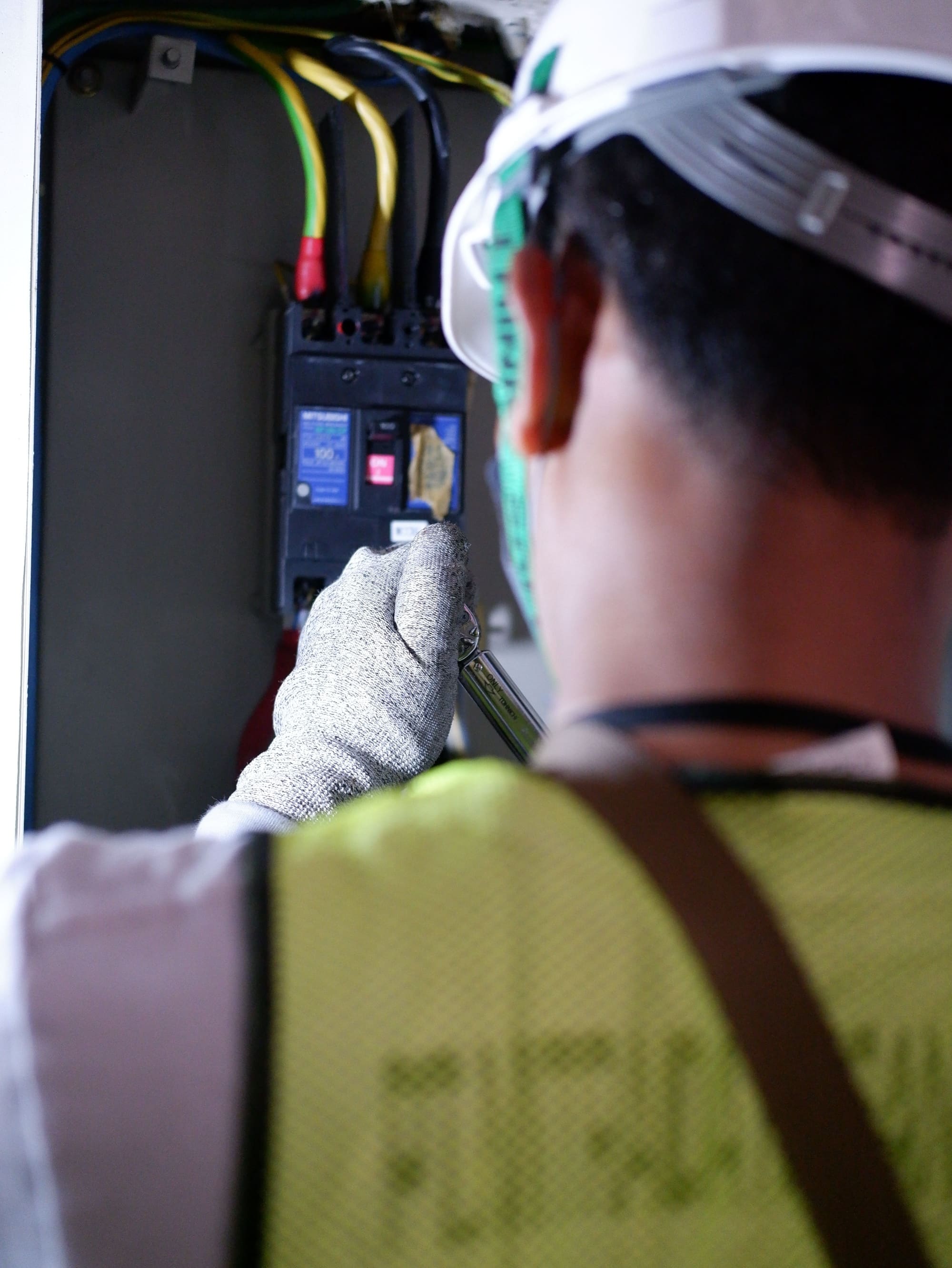 Una mano enguantada revisa un interruptor dentro de un tablero eléctrico abierto